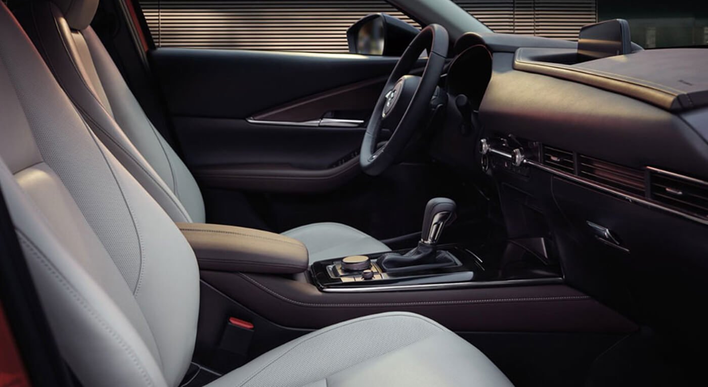 Empty driver’s seat with steering wheel and control console seen from passenger seat.