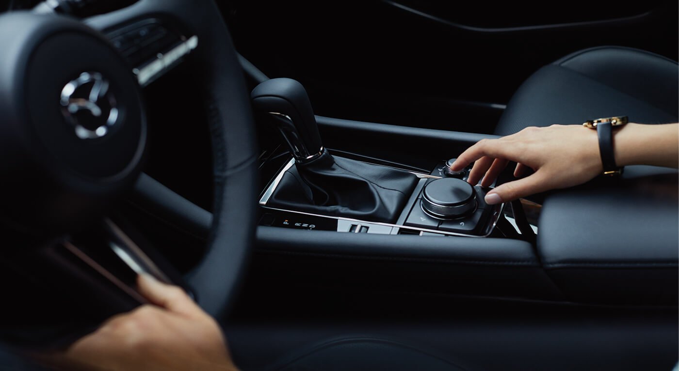 A female hand wearing a watch reaches down to the cockpit console to adjust a control.