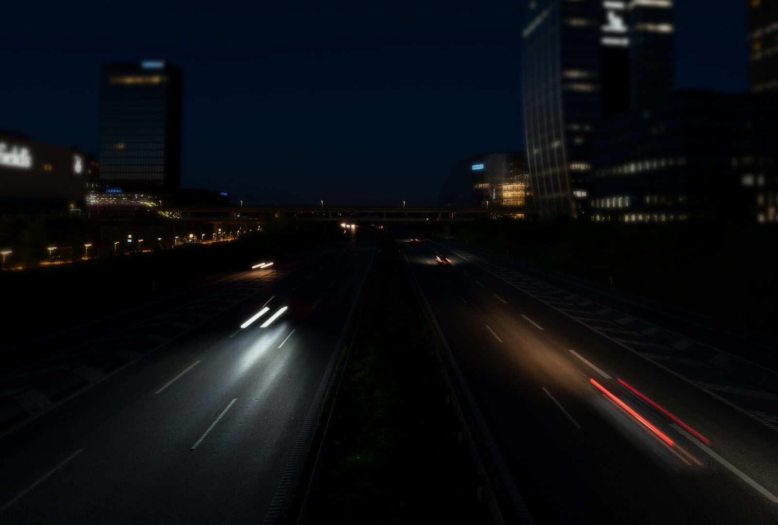 Blurry headlights and streaking taillights along urban thoroughfare at night. 