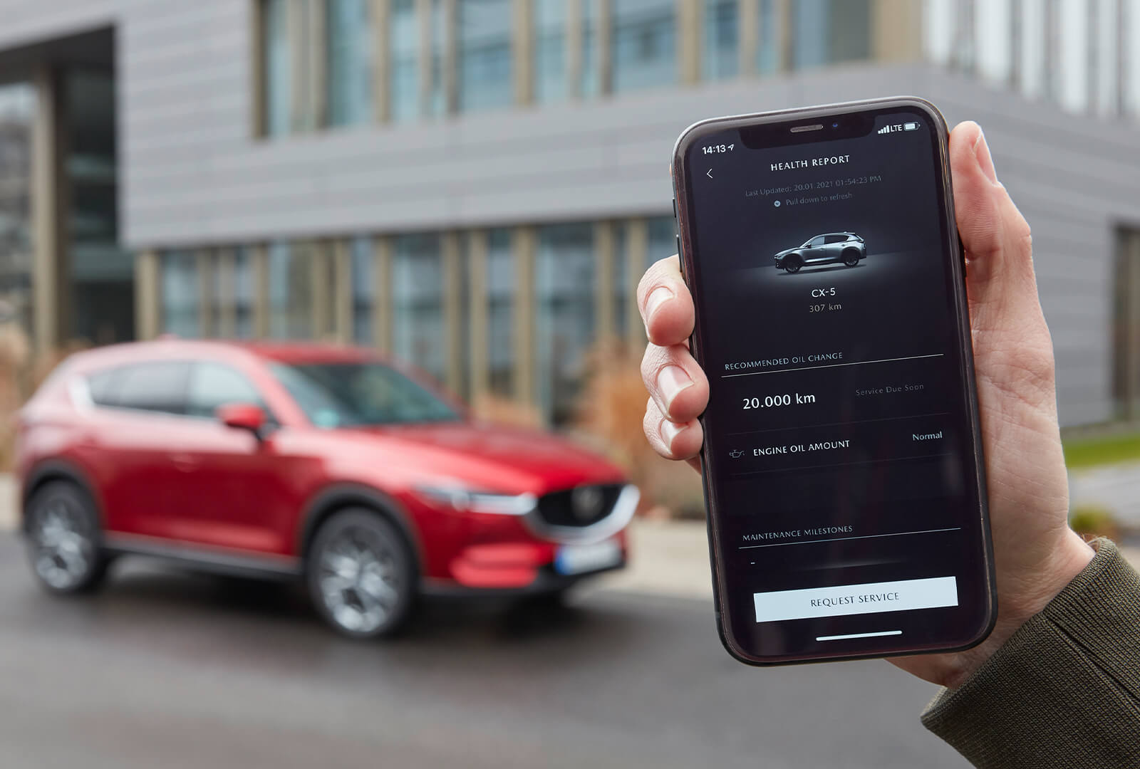 Main qui tient un téléphone intelligent avec l’application MyMazda affichant de l’information sur un CX-5