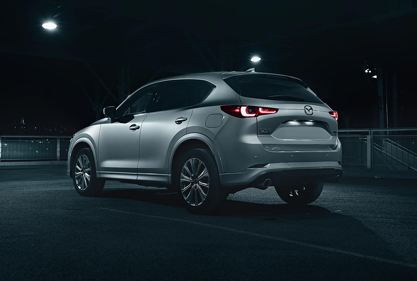 Rear view of CX-5 at night inside parking structure, rear lights on. 