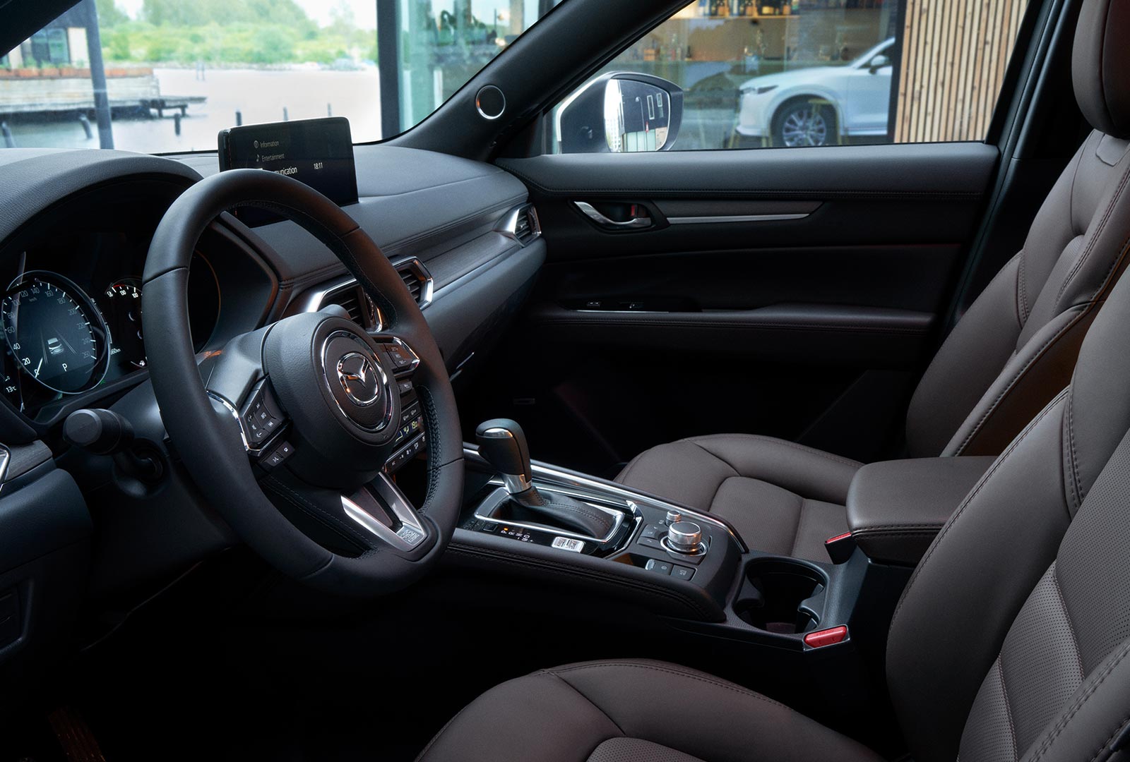 Interior CX-5 cockpit view of steering wheel, console with HMI Commander switch and Cocoa leather seats. 