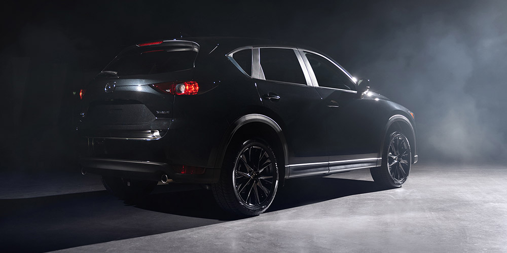 Jet Black Mica CX-5 in smoky, hard lit warehouse.