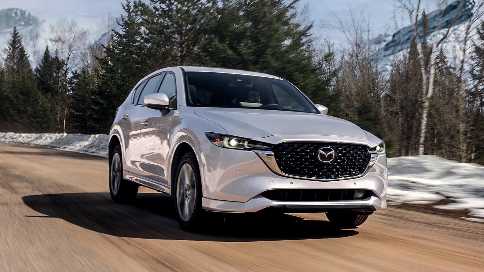 Rhodium White Metallic CX-5 driving down wintery country road. 