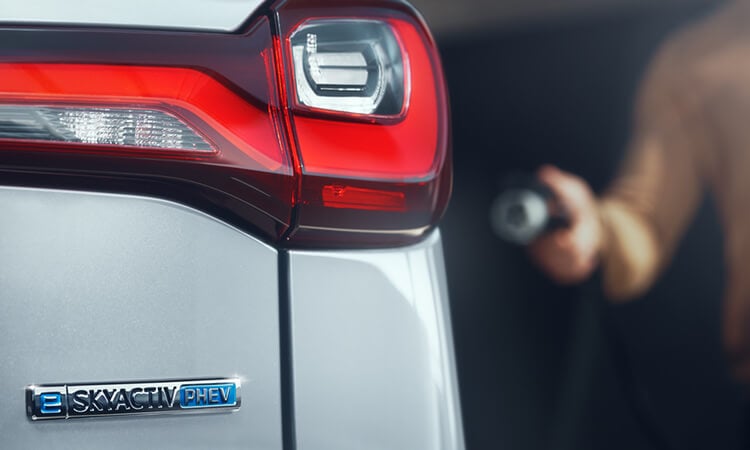 Driver approaches Mazda with level 2 charger in hand.