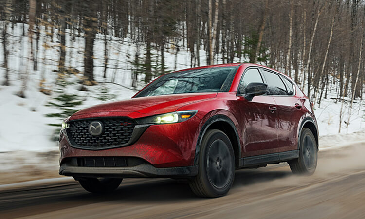 Soul Red Crystal Metallic Mazda CX-5 driving down wintery country road. 