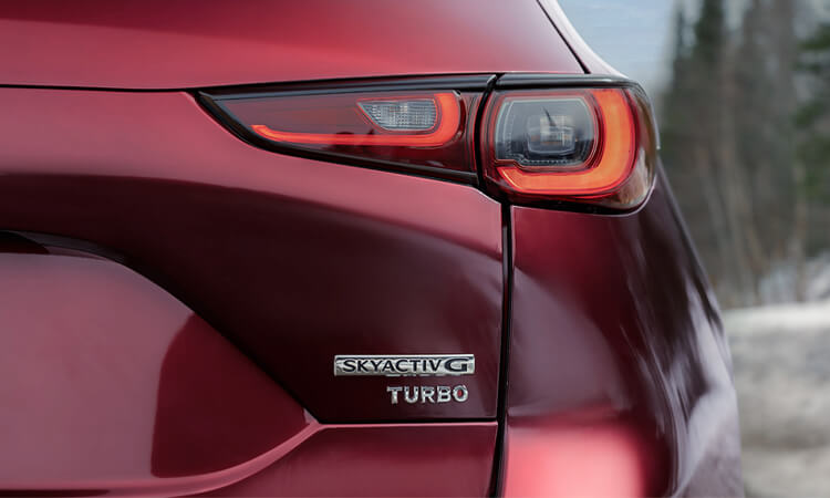 Close up of SkyactivG Turbo badge on rear hatch of Soul Red Crystal Metallic Mazda CX-5. 