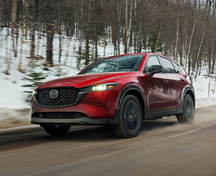 Soul Red Crystal Metallic Mazda CX-5 driving down wintery country road. 