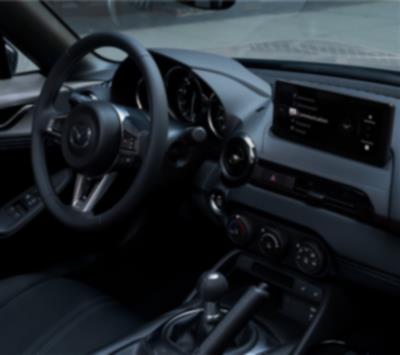 A driver in sunglasses uses their right hand to adjust settings on the dashboard controls.